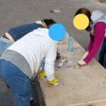 Bambini puliscono le panche imbrattate dai murales su via Puglie a Roma