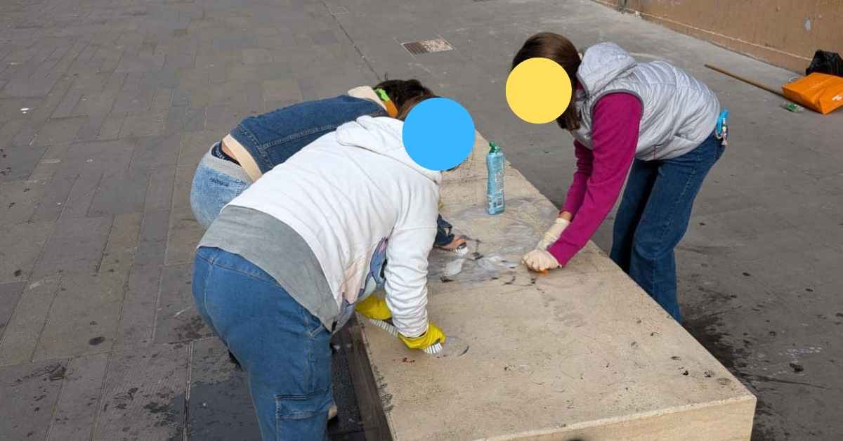 Bambini puliscono le panche imbrattate dai murales su via Puglie a Roma